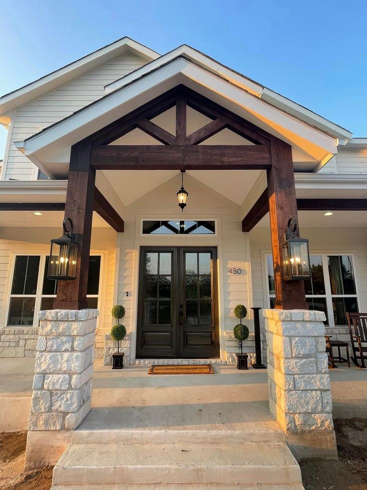 the front entrance to a home with stone steps and pillars on either side, leading up to it's entry door