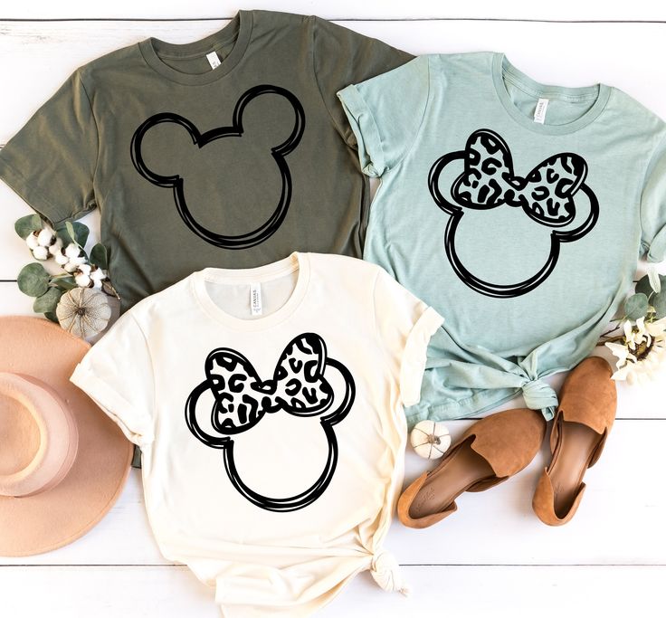 three t - shirts with mickey mouse heads on them and hats next to each other