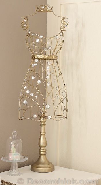 a gold sculpture with pearls on it sitting on top of a white table next to a wall