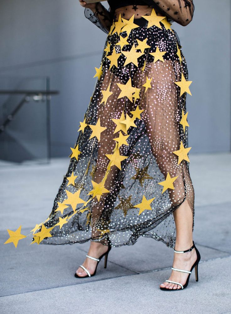 a woman in a sheer dress with stars on her skirt and heels, holding a cell phone