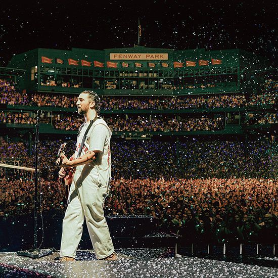 a man standing on top of a stage in front of a crowd with a guitar