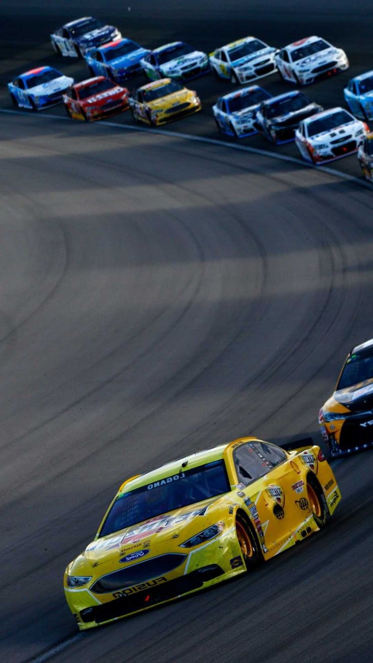 two cars racing on a race track with other cars in the background and one driving behind them