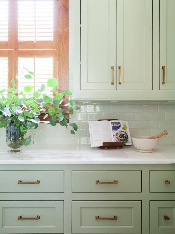 a kitchen with white cabinets and green plants in the window sill on the counter