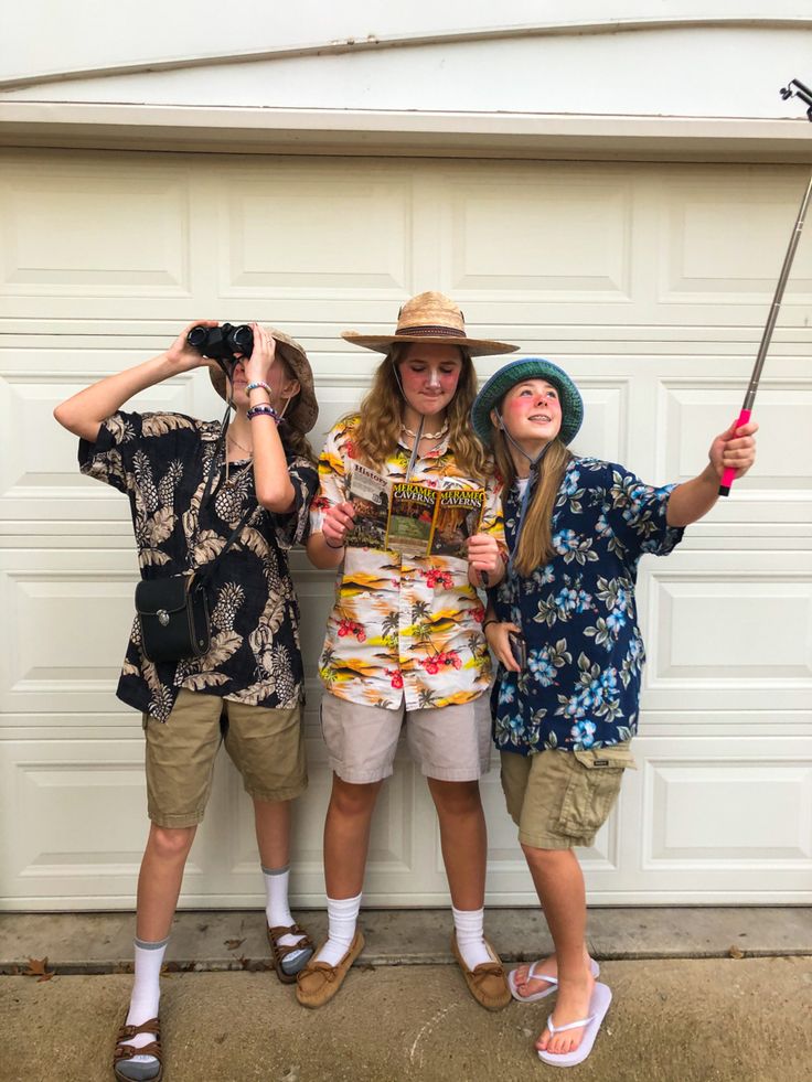 three young people standing next to each other in front of a garage door holding umbrellas