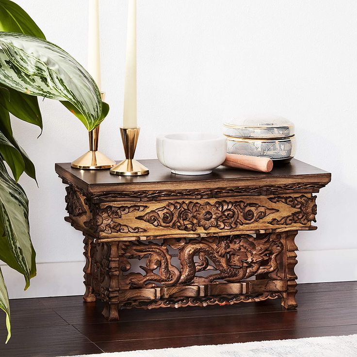 a wooden table topped with a bowl and two candles