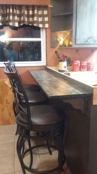 a kitchen with a bar and stools in it, next to a window that looks out onto the outside