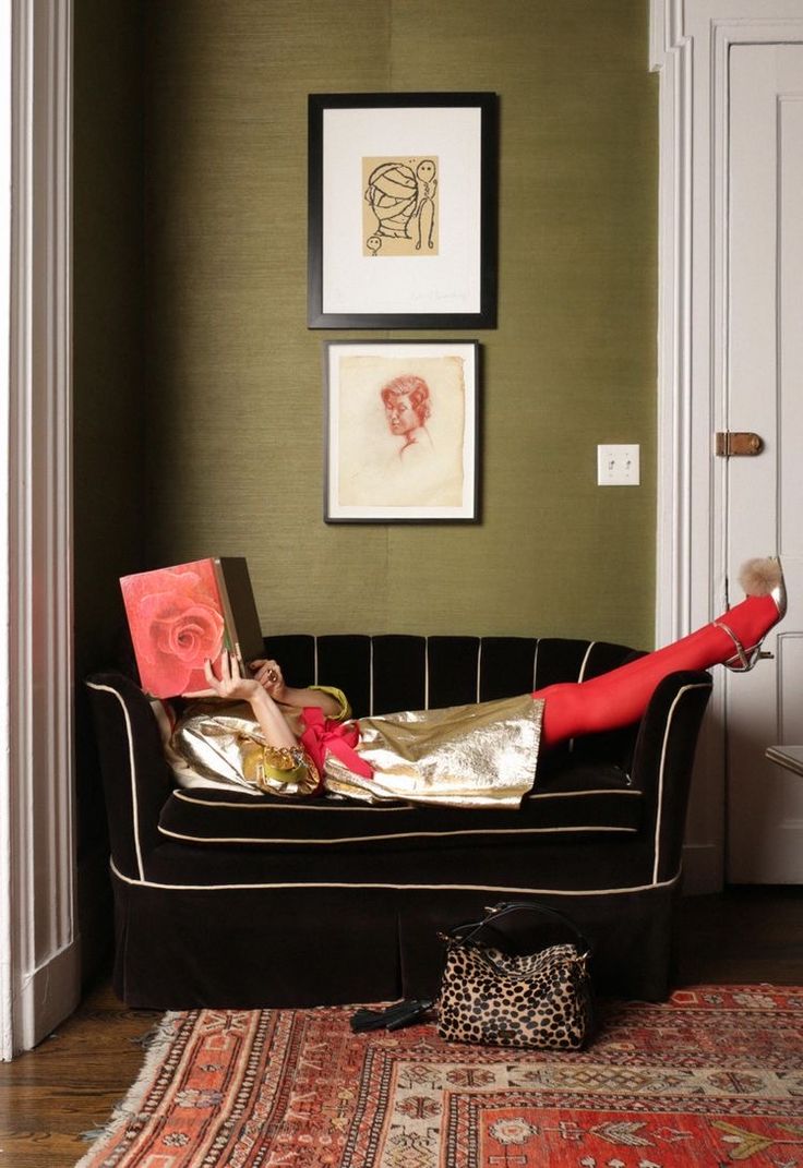 a woman laying on top of a black couch