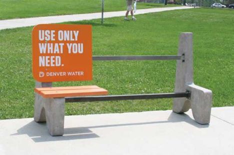 an orange sign sitting on top of a cement bench next to a grass covered park