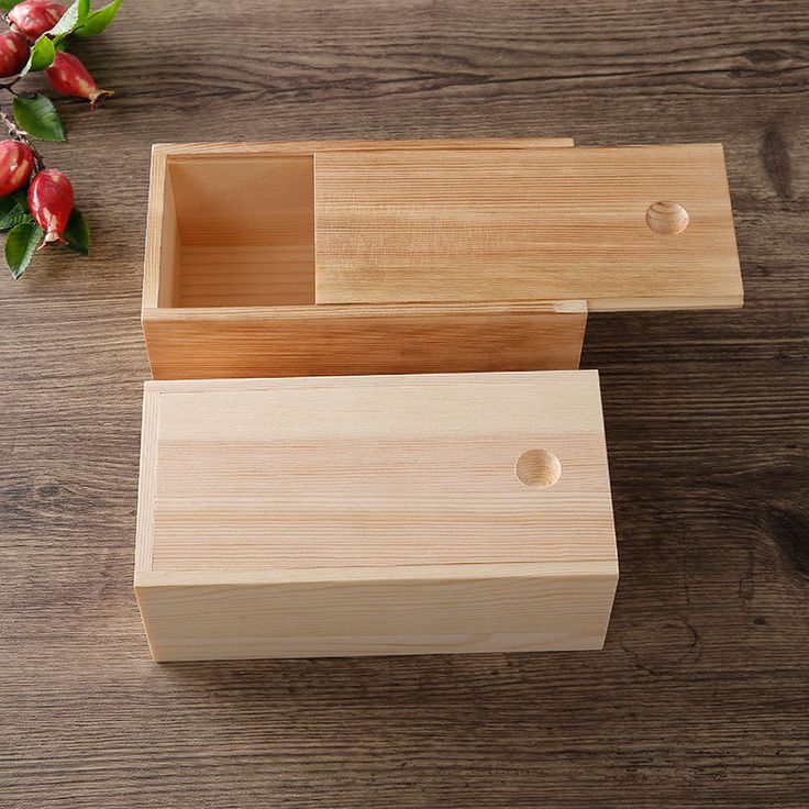 an empty wooden box sitting on top of a wooden table next to flowers and leaves