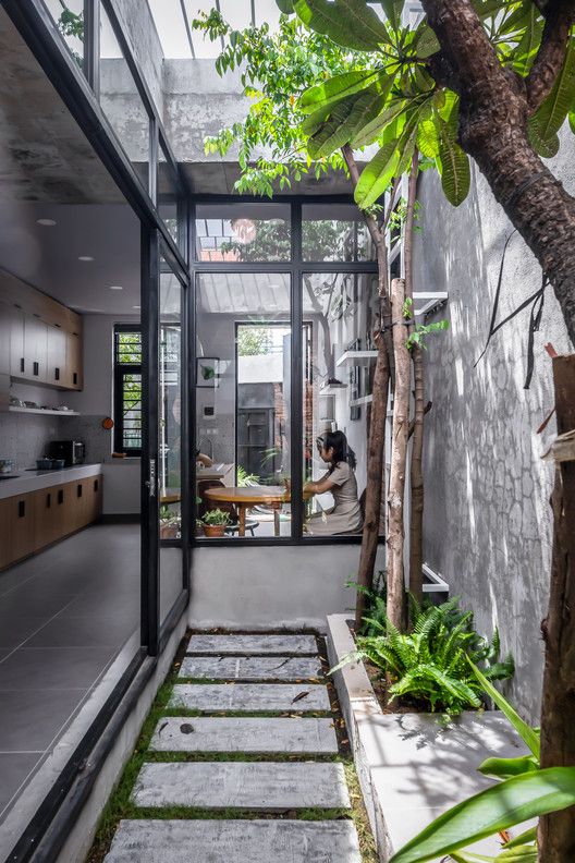 a person sitting at a table in a room next to a tree and some plants