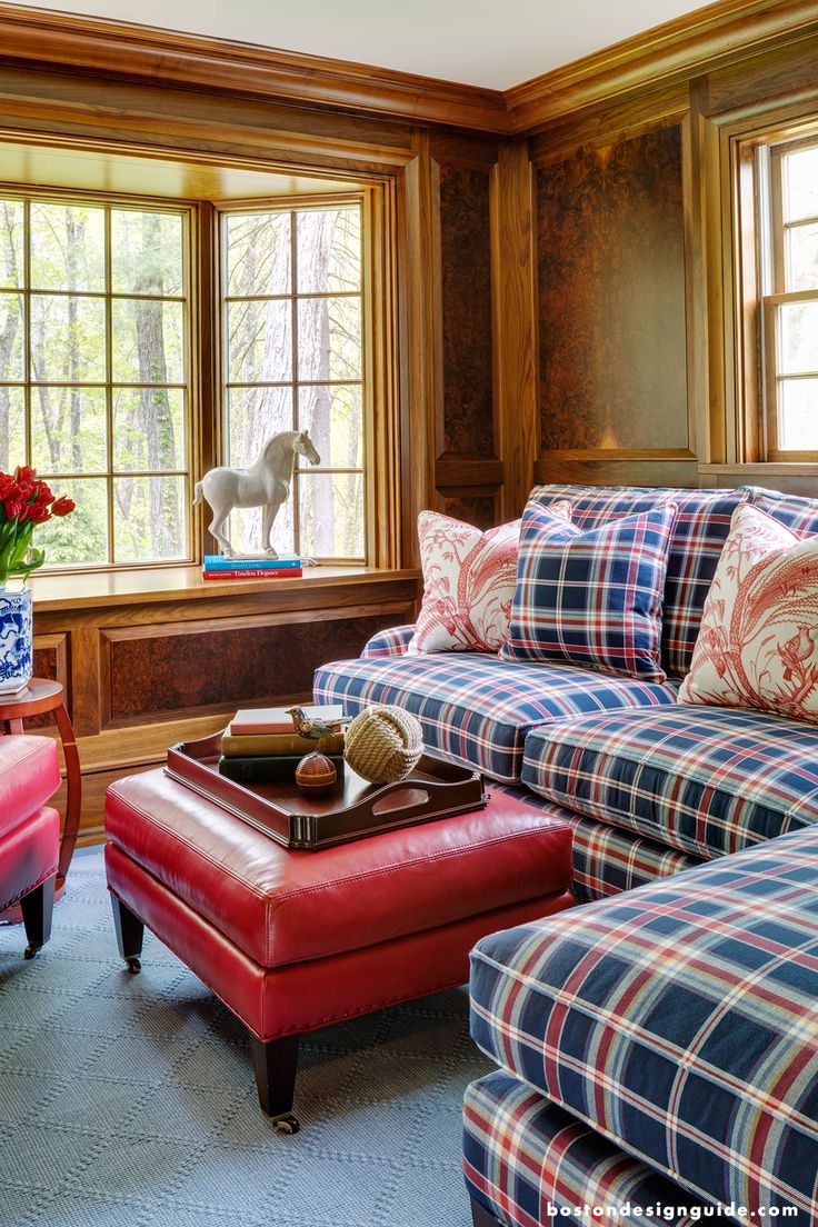 a red ottoman sitting in front of a window next to a blue couch and chair