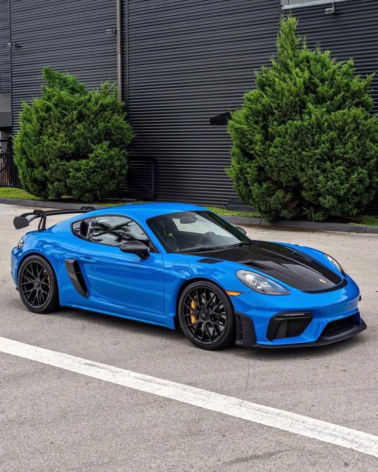 a blue sports car is parked in front of a building with black rims on it