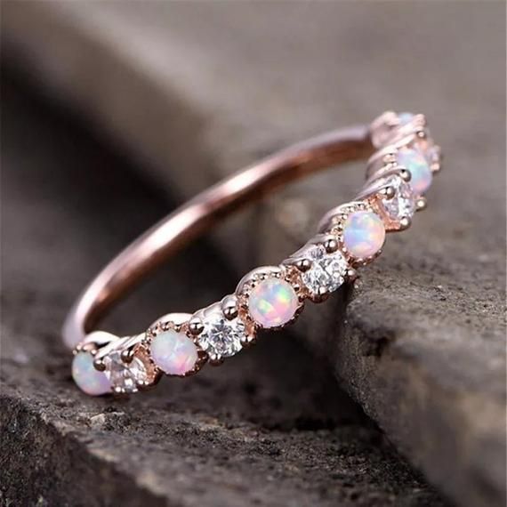 an opal and diamond ring sits on a rock