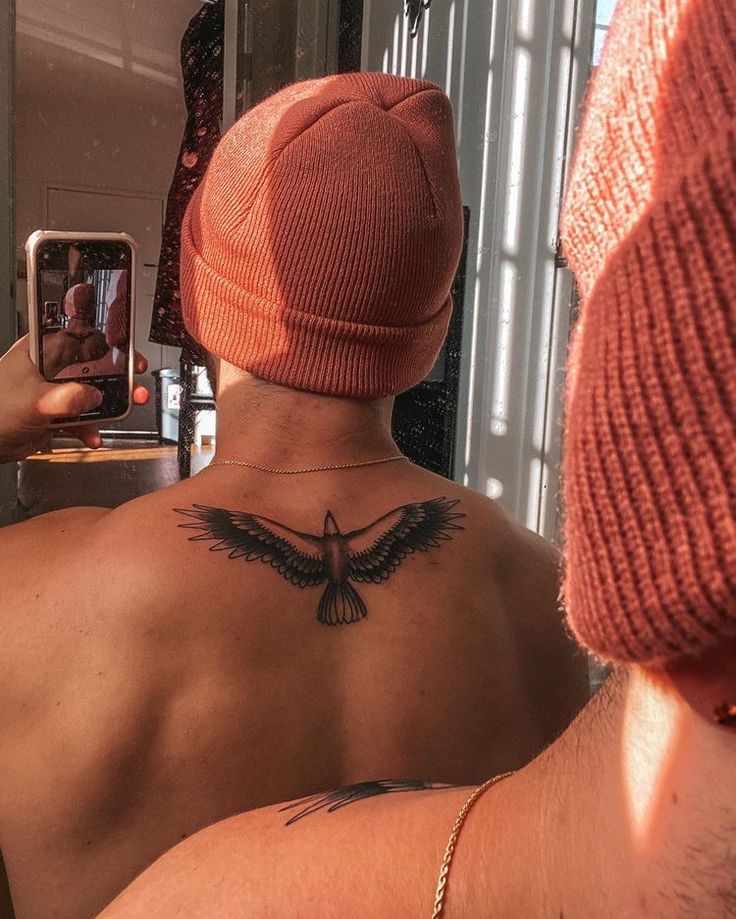 a man with a tattoo on his back taking a selfie in front of a mirror