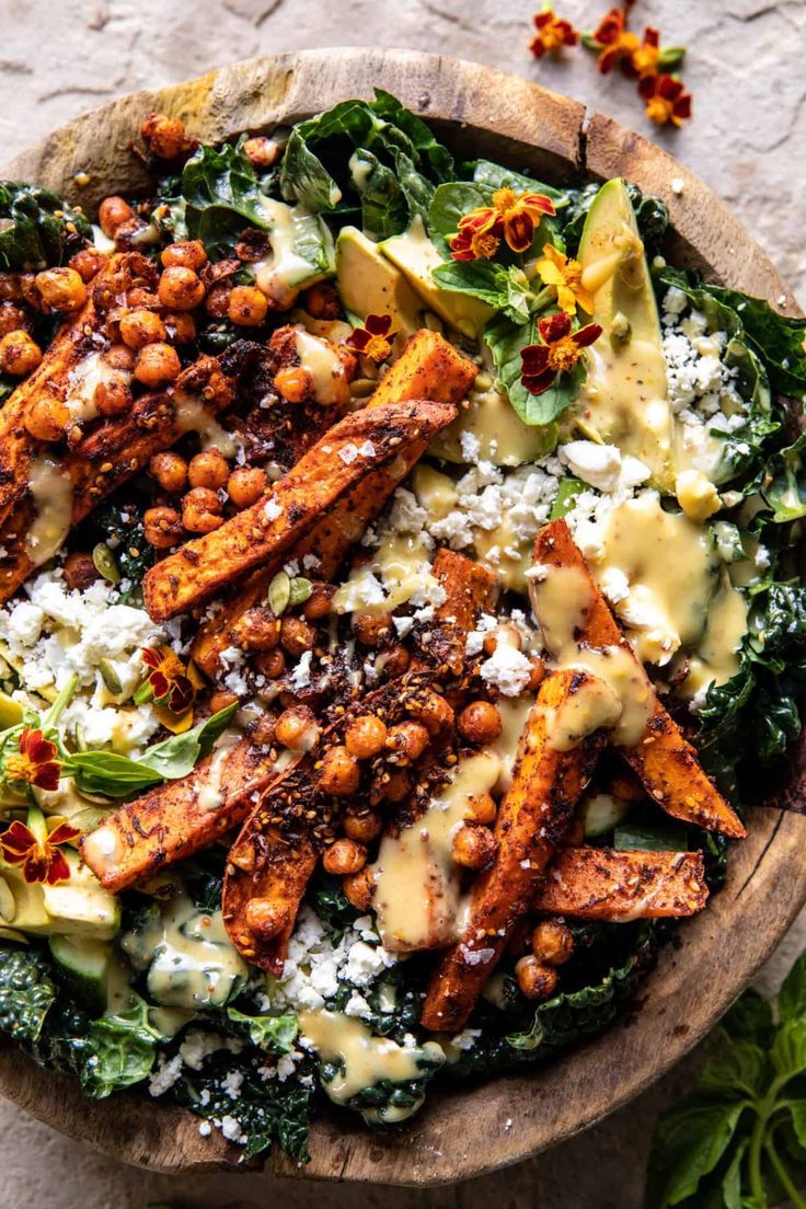 a salad with chickpeas, lettuce and cheese on top is served in a wooden bowl