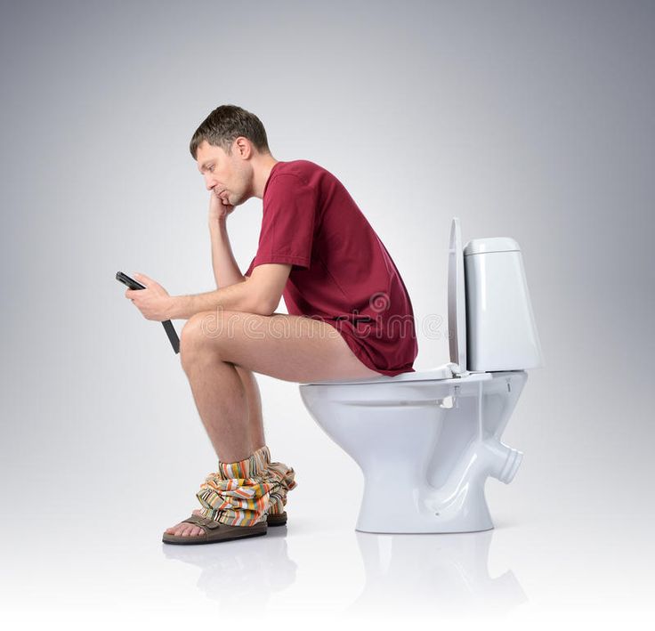 a man sitting on a toilet with his cell phone in his hand and looking at the screen