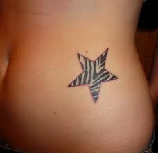 a zebra print star tattoo on the side of a woman's stomach, which is black and white