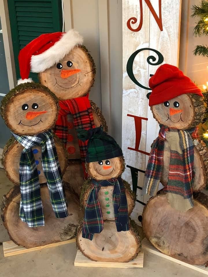 three snowmen with hats and scarves are sitting on logs