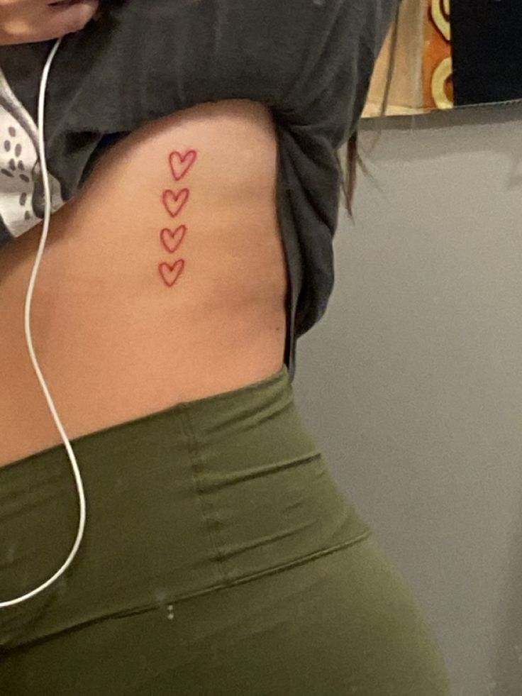 a woman with her back turned to the camera and has hearts tattooed on her stomach