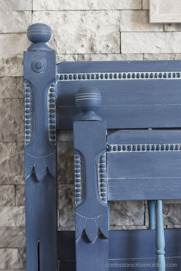 an old blue painted bench in front of a brick wall and stone fireplace mantel