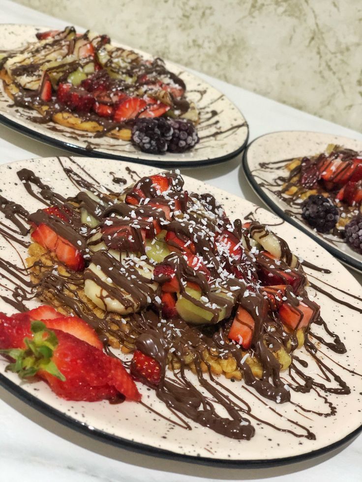 three plates with chocolate covered desserts and strawberries on the plate next to each other