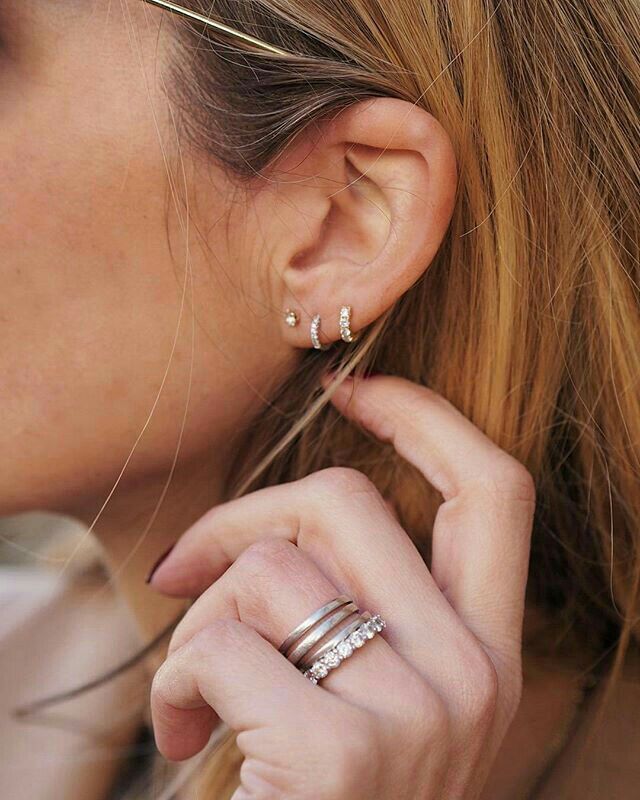 a close up of a person wearing two rings on their ear and one ring in the other hand