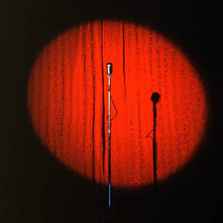 a microphone is shown in the middle of a dark room with red light coming from behind it