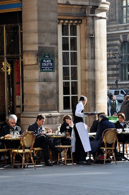 people are sitting at tables in front of an old building