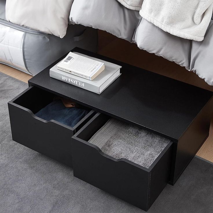 a black coffee table with two drawers on top and a book in the bottom drawer