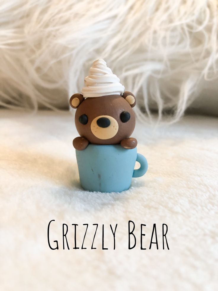 a brown bear sitting in a blue cup with a white hat on its head and the words grizzly bear above it