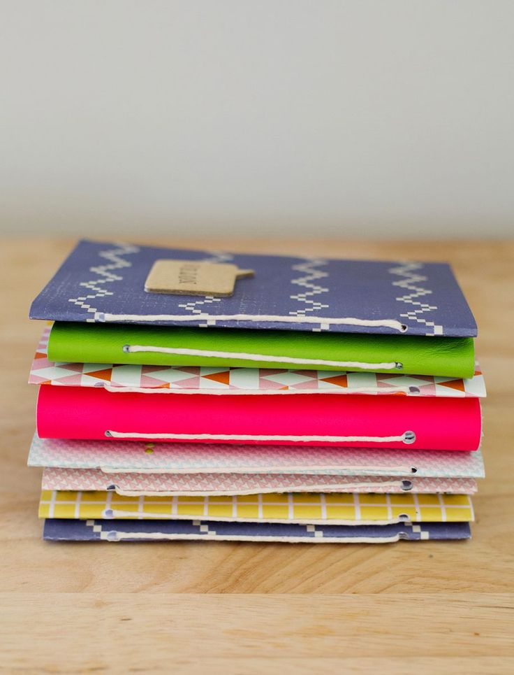 a stack of notebooks sitting on top of a wooden table next to each other