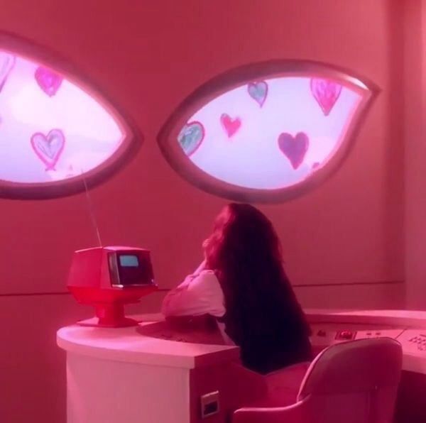 a woman sitting at a desk in front of two windows with hearts drawn on them