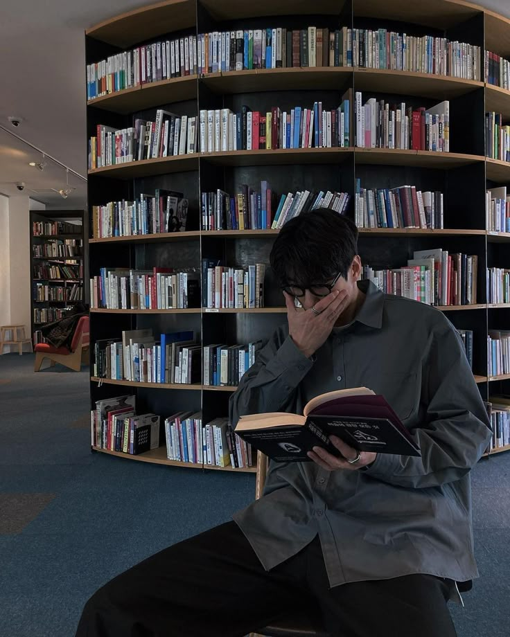 a man sitting in front of a bookshelf with his head on his hands