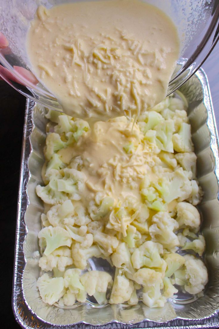 a person pouring sauce on some food in a pan