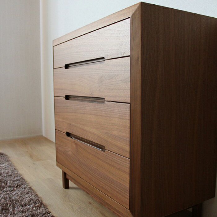 a wooden dresser sitting on top of a hard wood floor next to a white wall