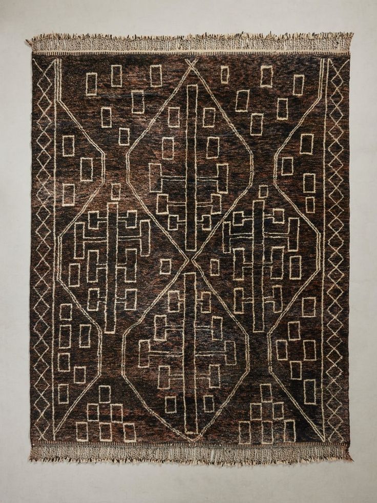 an old rug is hanging on the wall, with fringes around it and square shapes