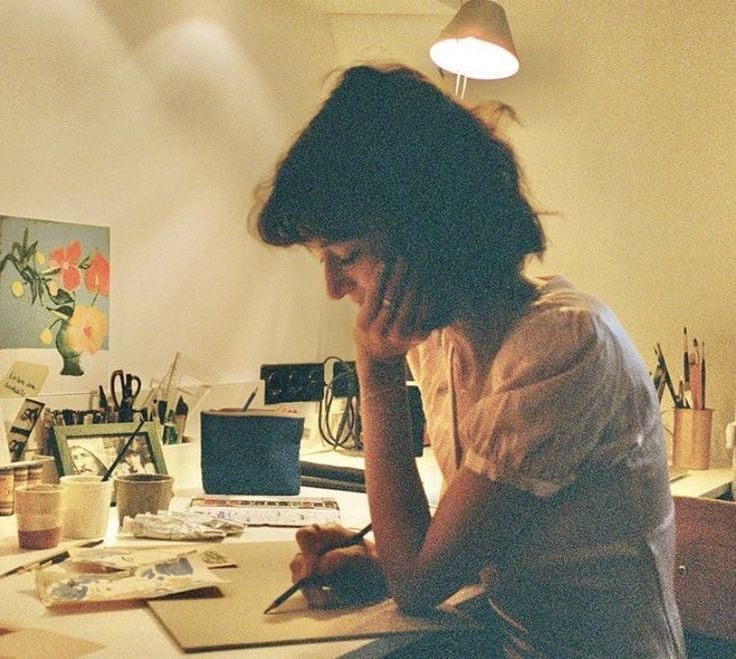 a woman sitting at a desk writing on a piece of paper