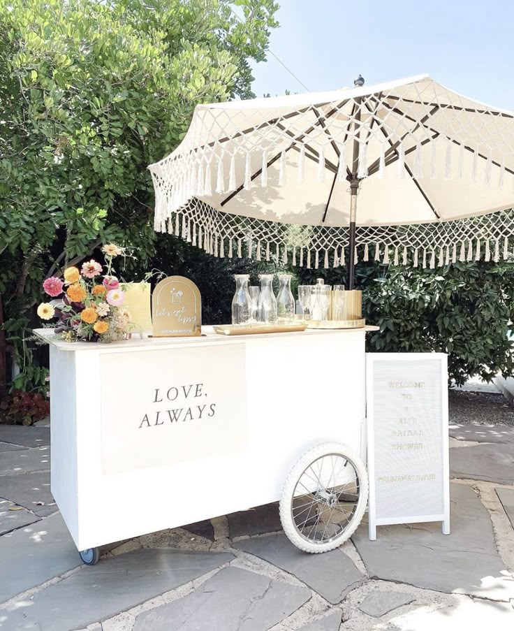 an ice cream cart is set up outside with flowers and vases on the table