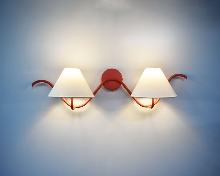 two lamps are on the wall next to each other, one is red and the other is white