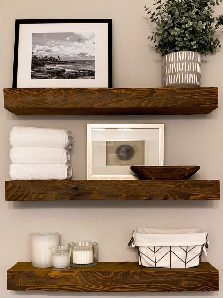 two wooden shelves holding towels, candles and pictures