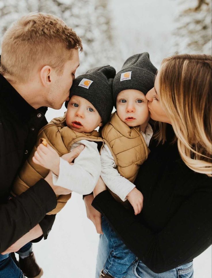 a man and woman kissing their baby boy in the snow