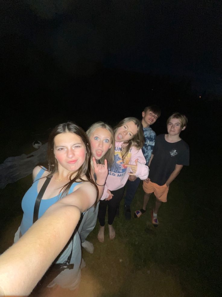 a group of people standing next to each other on a field at night with one person taking a selfie