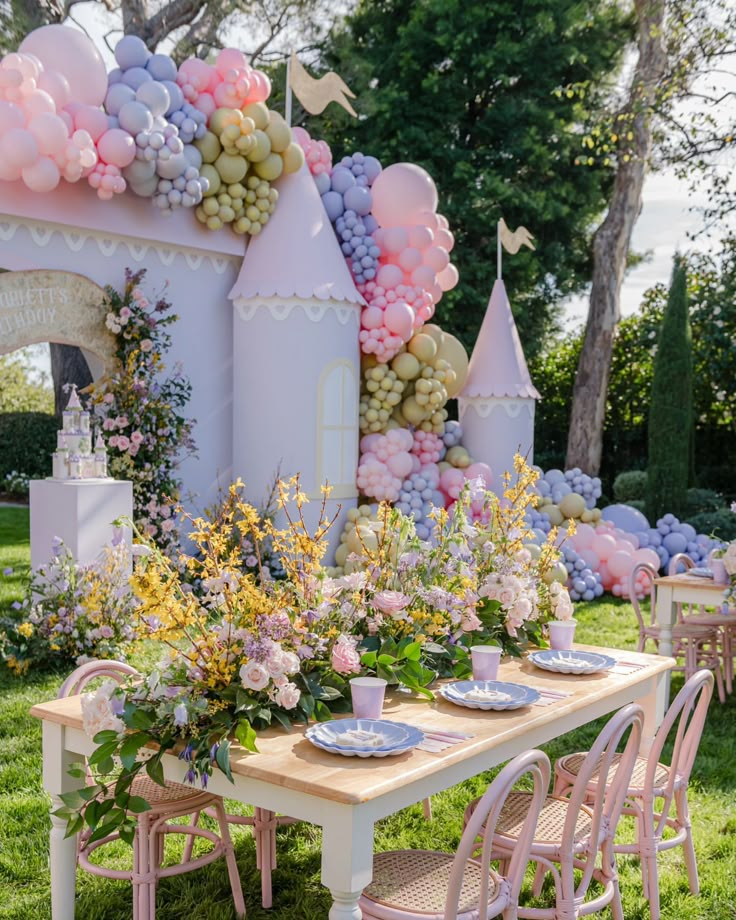 a table set up for a party with balloons and flowers