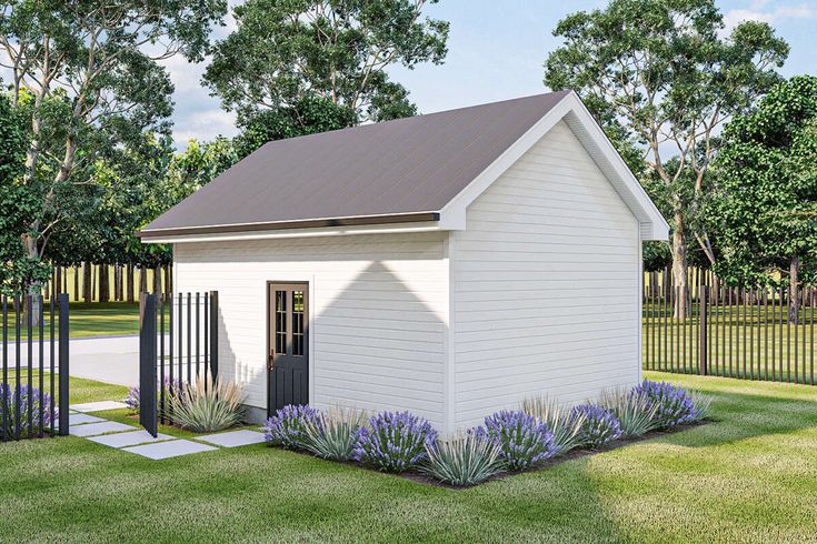 a small white shed sitting on top of a lush green field next to a fence