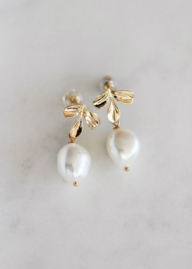 two pairs of gold and white pearl earrings on a marble surface, with the top bead off