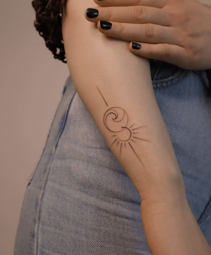 a woman's arm with a small sun tattoo on the left side of her arm