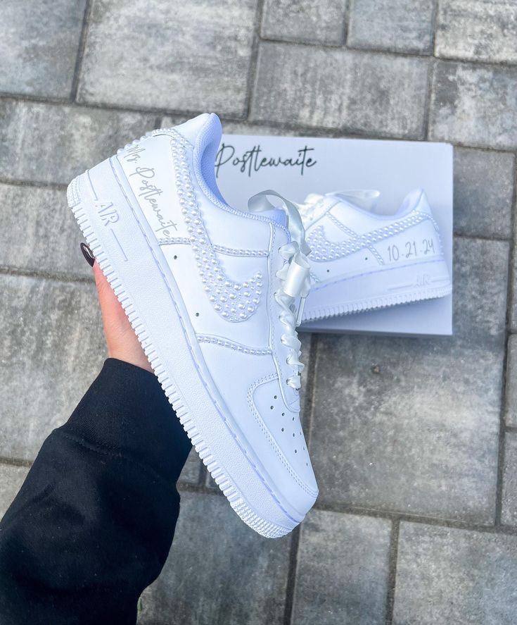 Blinged out bridal Air Force 1 sneakers personalized for the brides special day 👰🏻 **PLEASE READ LISTING CAREFULLY**  SNEAKERS: This listing if for Nike Air Force 1, if you would like something different please message me :) Personalization section please add: *your name  *date of wedding *if you want them without any customization please type (no customization) NOTE: A proof of your lettering will be sent to you within 72 hours of purchasing, please check your messages to approve image. If seller does not hear back within another 48 hours will proceed with shoes accordingly.  Price breakdown: *Outer Side/Seam $245      -This option includes all white pearls on the 2 outer symbols, the outer 2 side seams, pearls going up the back heel strip and the back seam & lettering of your choice. R Pearl Nike Air Force, Wedding Nike Air Force, Nike Bride Shoes, Bride Air Force Ones, White Sneakers With Laces For Bridal Shower, White Low-top Bridal Sneakers, White Low-top Wedding Shoes For Bride, White Low-top Wedding Shoes For Bridal Shower, Custom White Sneakers With Round Toe For Anniversary