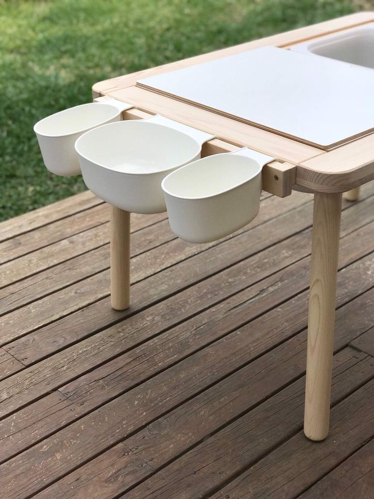 an outdoor table with three bowls on it and one bowl at the bottom, sitting on a wooden deck