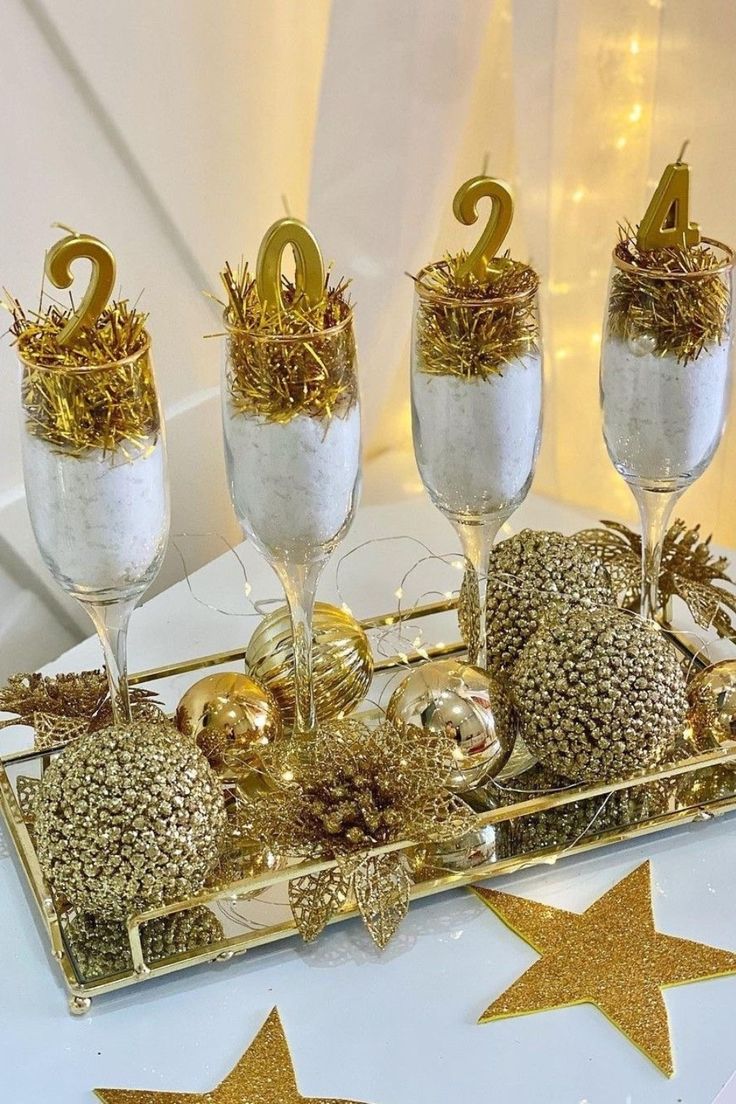 gold and white decorations on a tray with wine glasses in front of the number two