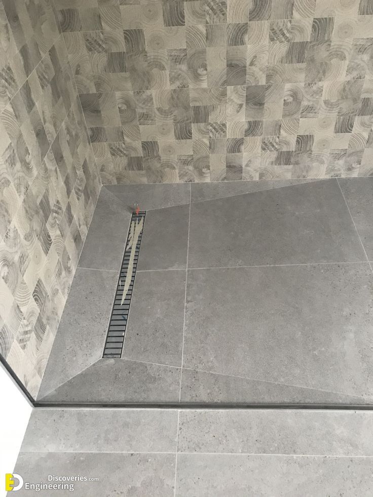 a tiled shower stall with a grate in the floor